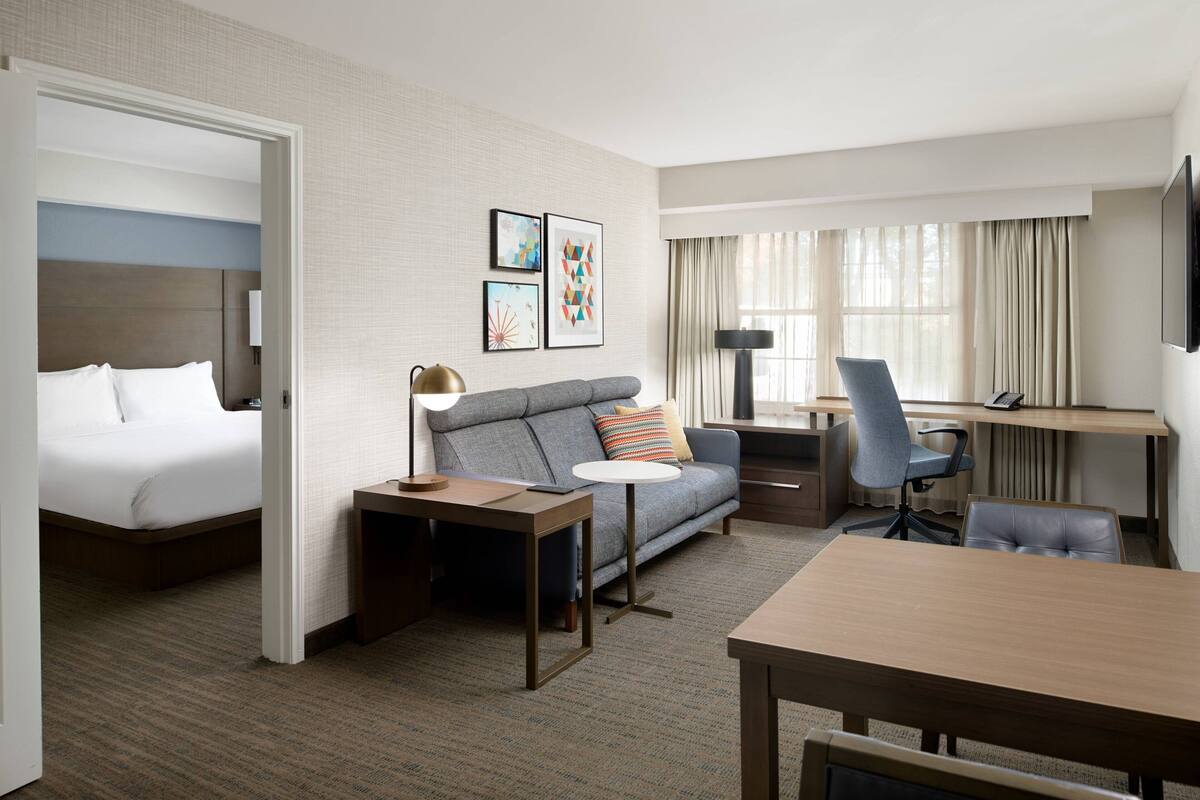 Una habitación de hotel con cama, sofá, escritorio y televisor.