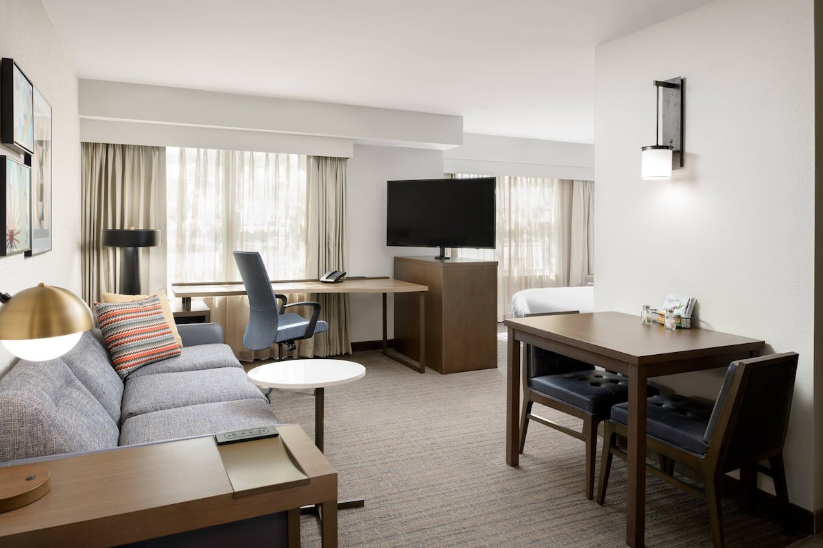 Une chambre d’hôtel équipée d’un canapé, d’une table à manger, d’une télévision et d’un bureau.