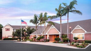 Ein Hotel mit Ziegelaußenwand, Palmen und einer amerikanischen Flagge.