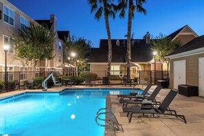 Una piscina al aire libre, sillones reclinables de piscina