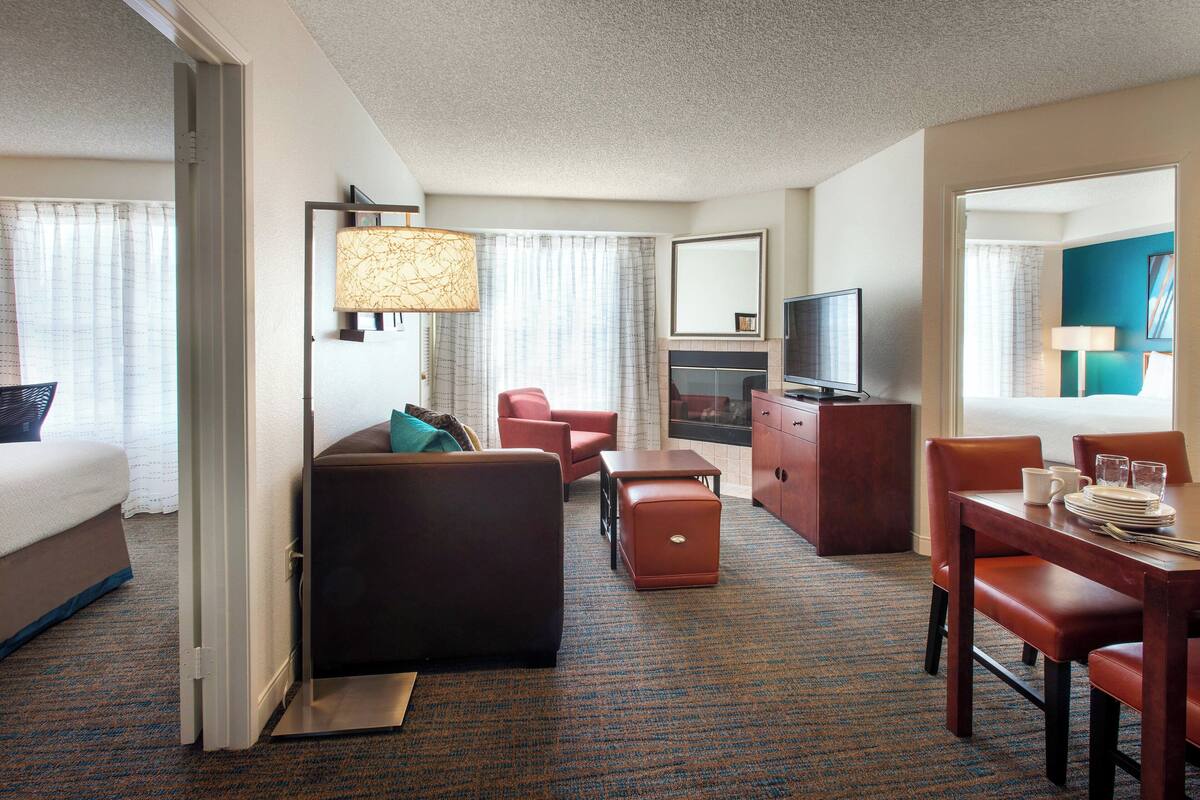 Ein Hotelzimmer mit Bett, Sofa, Schreibtisch, Fernseher und Essbereich.