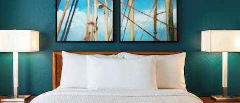 A hotel room with a bed, two wall-mounted paintings, and two bedside lamps.