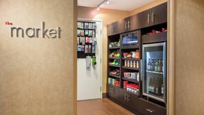 Ein Flur mit einem Automaten und gekühlten Regalen, gefüllt mit Getränken und Snacks.