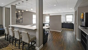 A modern kitchen with a bar area, a dining space with bar stools, and a kitchen counter. - Residence Inn by Marriott Louisville Airport (Louisville)