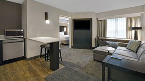 A modern hotel room with a kitchenette, a sofa, a dining area, and a TV. - Residence Inn by Marriott Louisville Airport (Louisville)