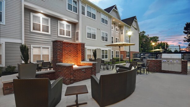 A hotel patio with outdoor seating, a brick fire pit, and a barbecue grill. - Residence Inn by Marriott Louisville Airport (Louisville)