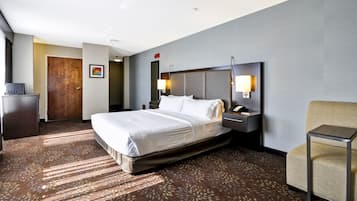 A hotel room with a large bed, bedside lamps, a desk, and a chair.