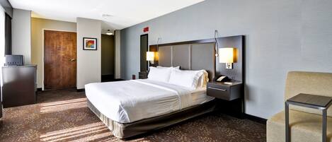 A hotel room with a large bed, bedside lamps, a desk, and a chair.