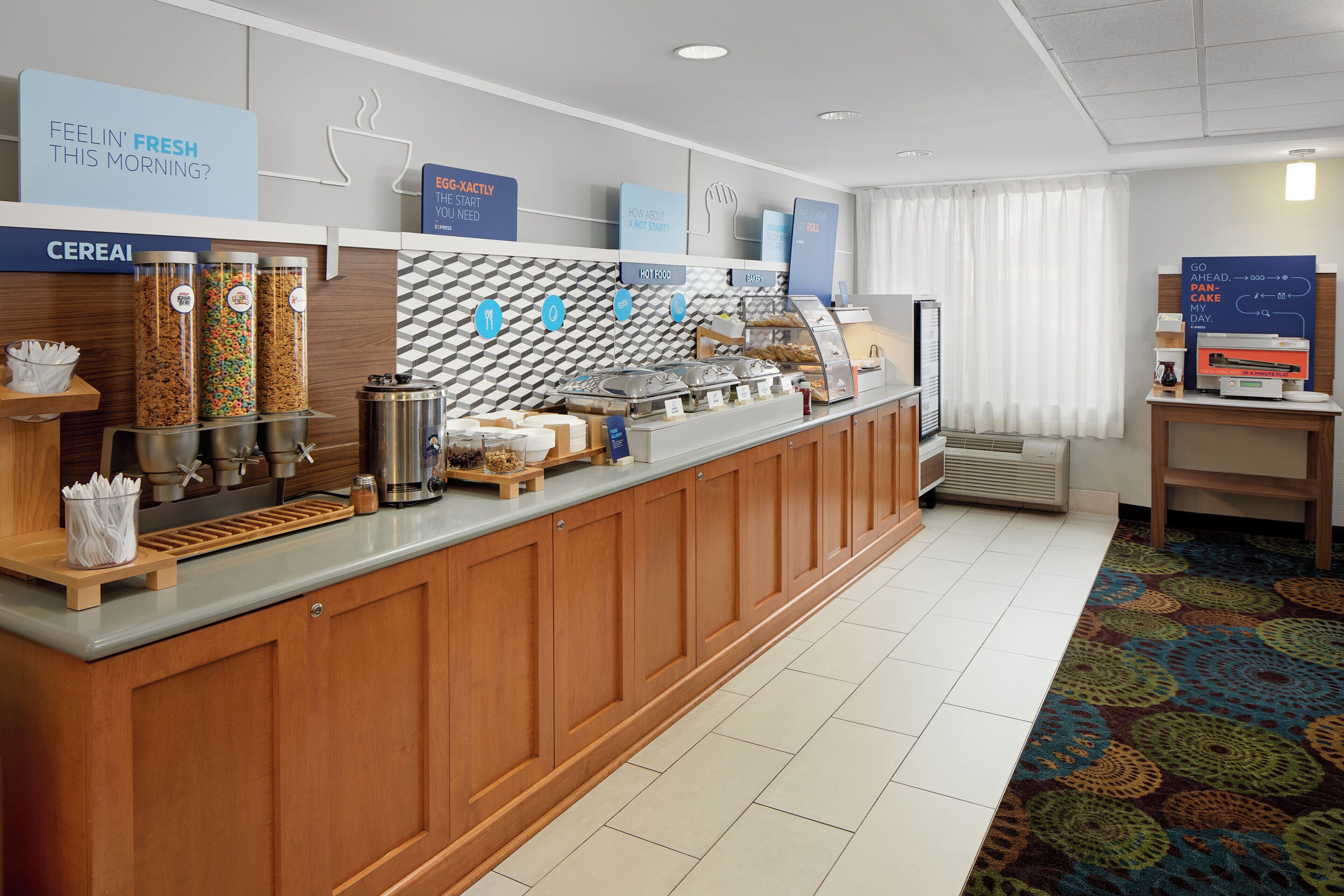 A breakfast bar with cereal, hot food, and bakery options.