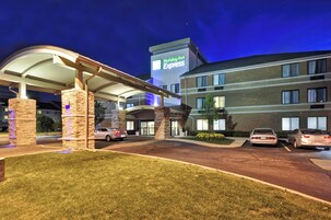 Un hotel Holiday Inn Express con área de estacionamiento techada y fachada de ladrillo.