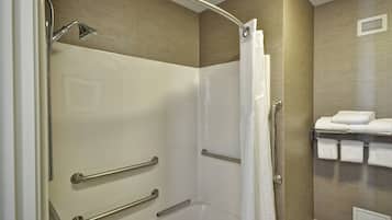 A modern bathroom with a walk-in shower, grab bars, a towel rack with neatly folded towels, and a wall-mounted vent.