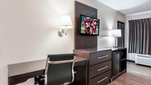A hotel room with a desk, chair, TV, lamp, and air conditioning unit. - Red Roof Inn Richmond, KY (Richmond)