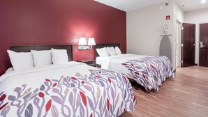 A hotel room with two beds, a red accent wall, a nightstand with lamps, and a door with a coat rack. - Red Roof Inn Richmond, KY (Richmond)
