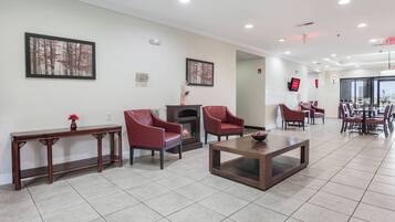A hotel lobby with a fireplace, seating area, and a dining section.