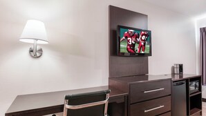 A hotel room with a flat-screen TV mounted on the wall, a desk with a chair, a lamp, and a coffee maker. - Red Roof Inn Richmond, KY (Richmond)