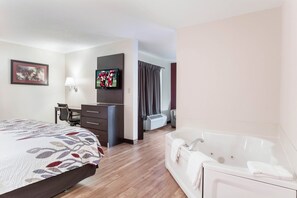 A hotel room with a bed, a desk, a TV, a bathroom with a bathtub, and a window with curtains. - Red Roof Inn Richmond, KY (Richmond)