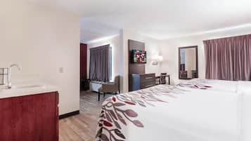 Una habitación de hotel con cama, escritorio, silla, televisor y baño.