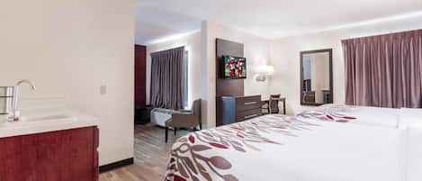 A hotel room with a bed, a desk, a chair, a television, and a bathroom.