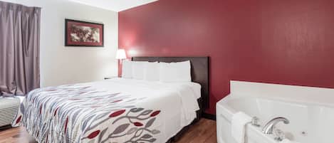 A hotel room with a bed, a bedside lamp, a large window with curtains, a wall-mounted picture, and a separate bathroom with a bathtub.