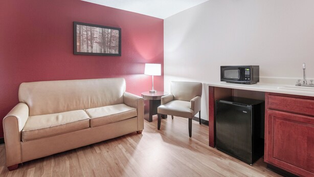 A compact kitchenette with a microwave, refrigerator, and a small dining area with a table and chair. - Red Roof Inn Richmond, KY (Richmond)
