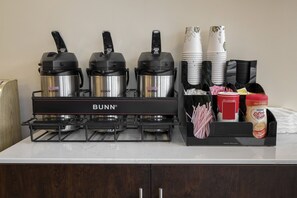 A kitchen area with a Bunn coffee maker, two coffee pots, a coffee machine, disposable cups, and a coffee maker box. - Red Roof Inn Richmond, KY (Richmond)
