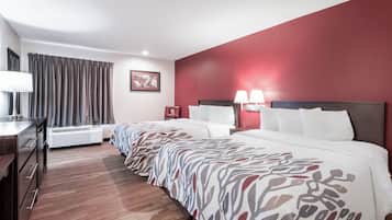 Ein Hotelzimmer mit Bett, Nachttischen, Schreibtisch, Stuhl, Lampe, einem Bild an der Wand und einem Fenster mit Vorhängen.