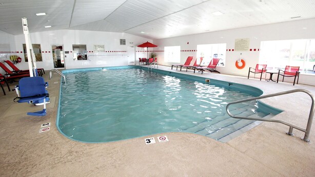 An indoor swimming pool with a 3ft depth marker, red lounge chairs, and a lifebuoy on the wall. - Hampton Inn Sandusky-Central (Sandusky)