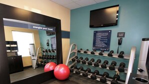 A gym with exercise equipment, a TV, and informational posters on the wall. - Hampton Inn Sandusky-Central (Sandusky)