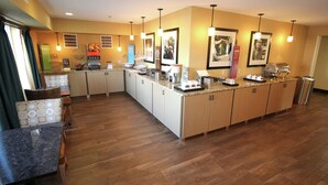 A modern kitchen with wooden cabinets, a marble countertop, and pendant lighting. - Hampton Inn Sandusky-Central (Sandusky)