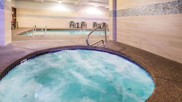 Un jacuzzi con borde de azulejos, una zona de estar con sillas y una pared de azulejos con diseño de piedras.