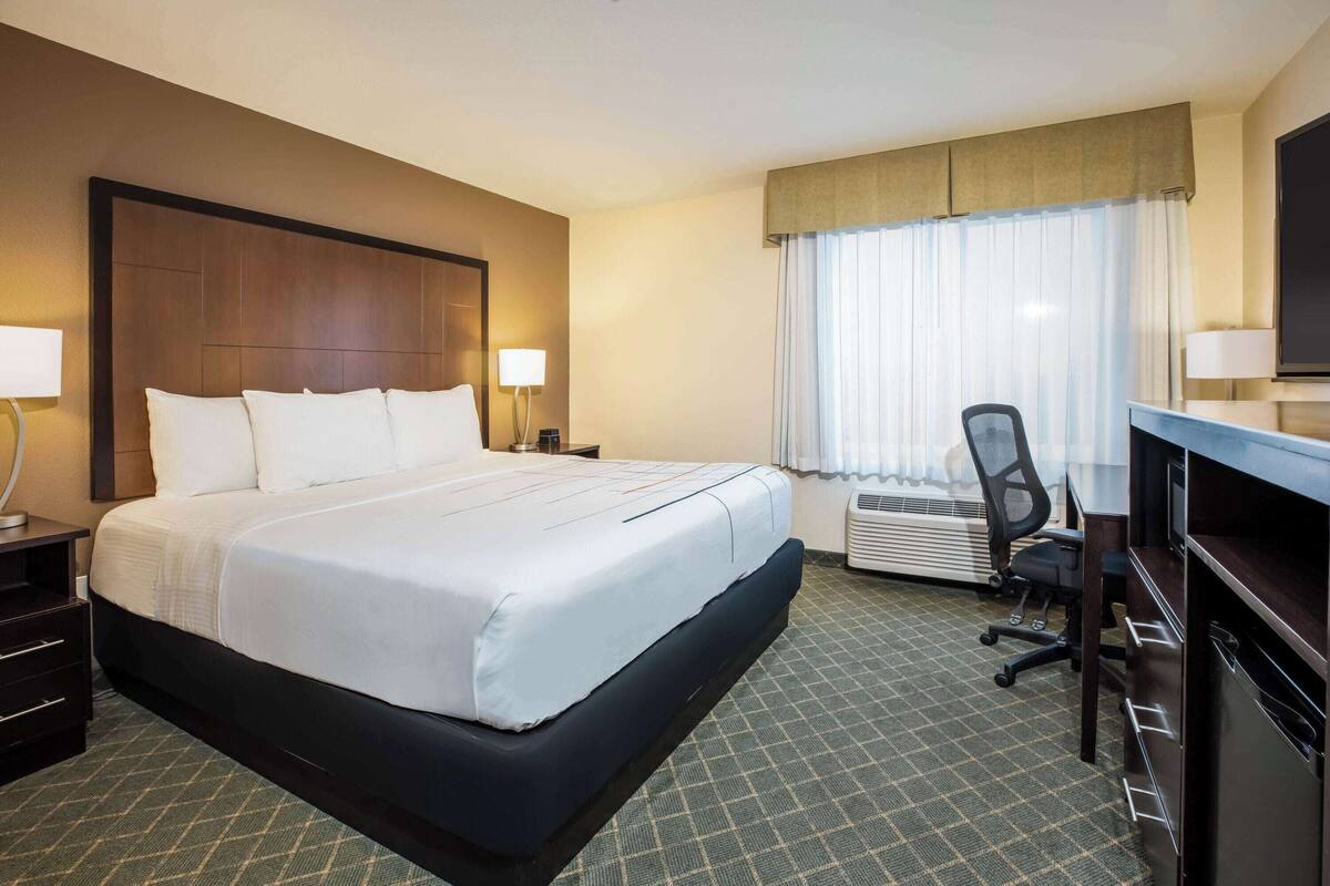 Una habitación de hotel con una cama grande, un escritorio, una silla y un televisor.