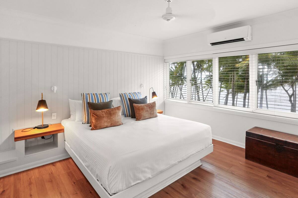 A bedroom with a bed, bedside tables, a nightstand, a dresser, and a window with blinds.