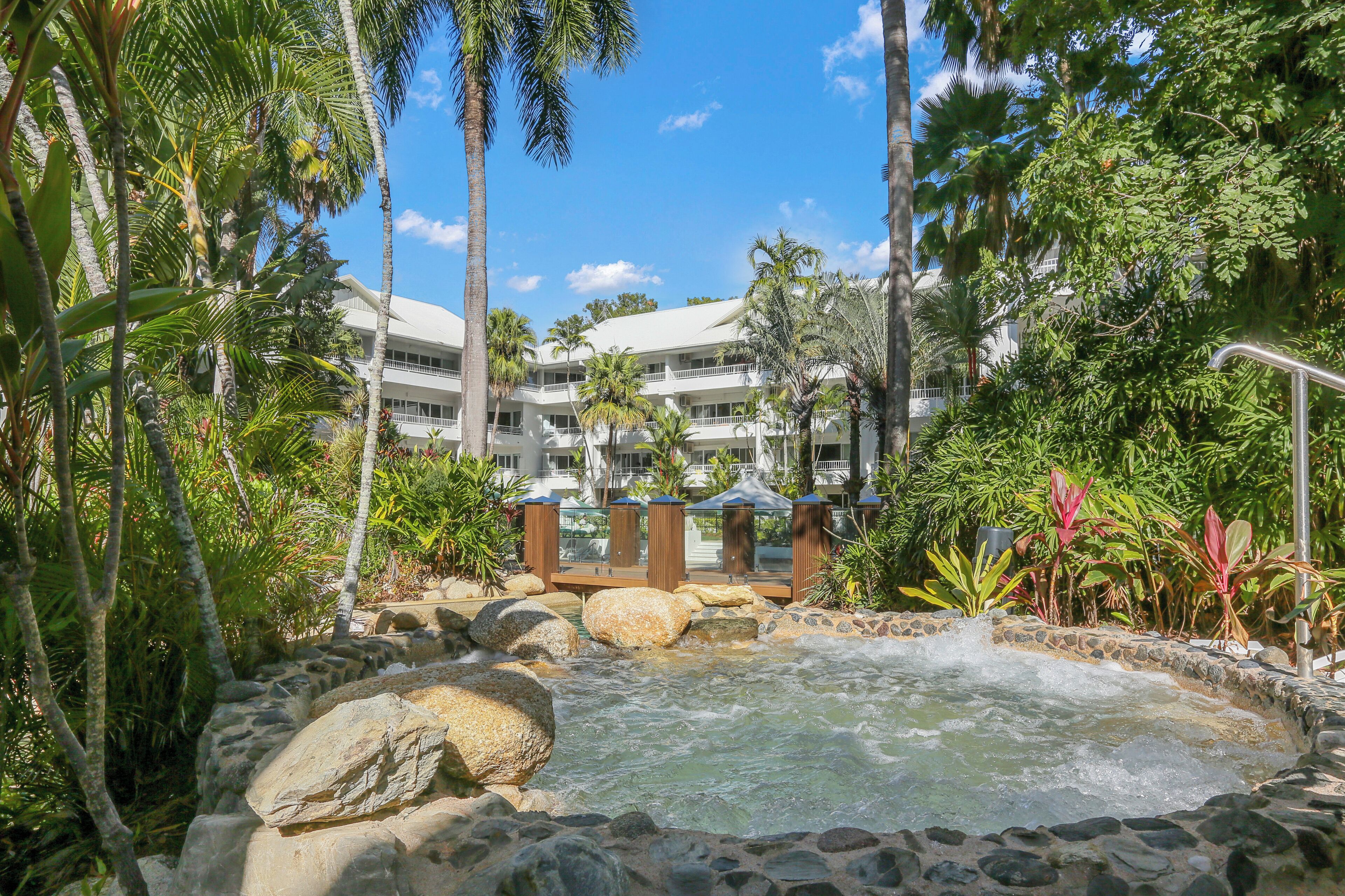A resort with a hot spring surrounded by tropical vegetation and palm trees.
