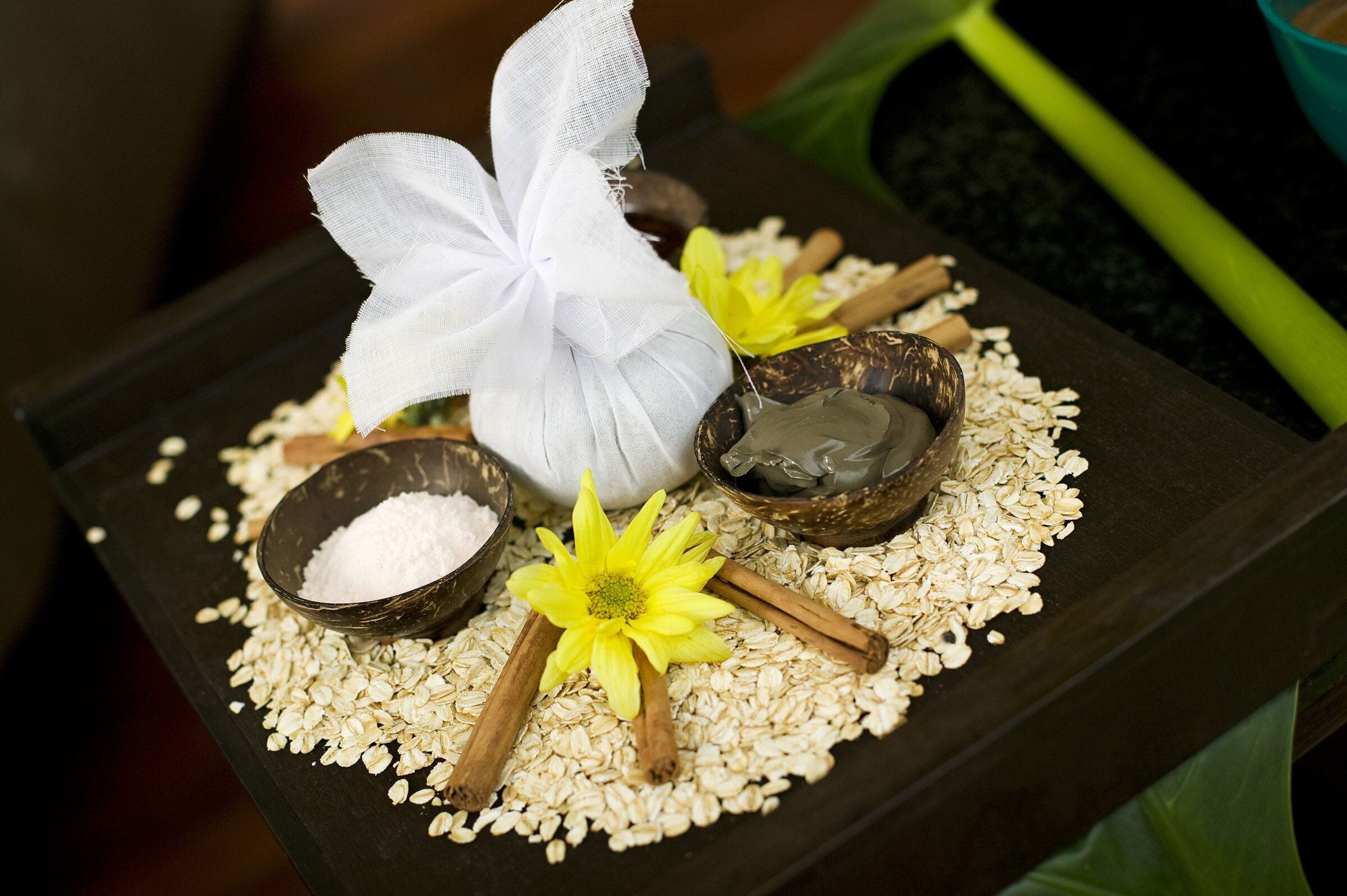 A tray with oats, cinnamon sticks, a flower, and a white cloth.
