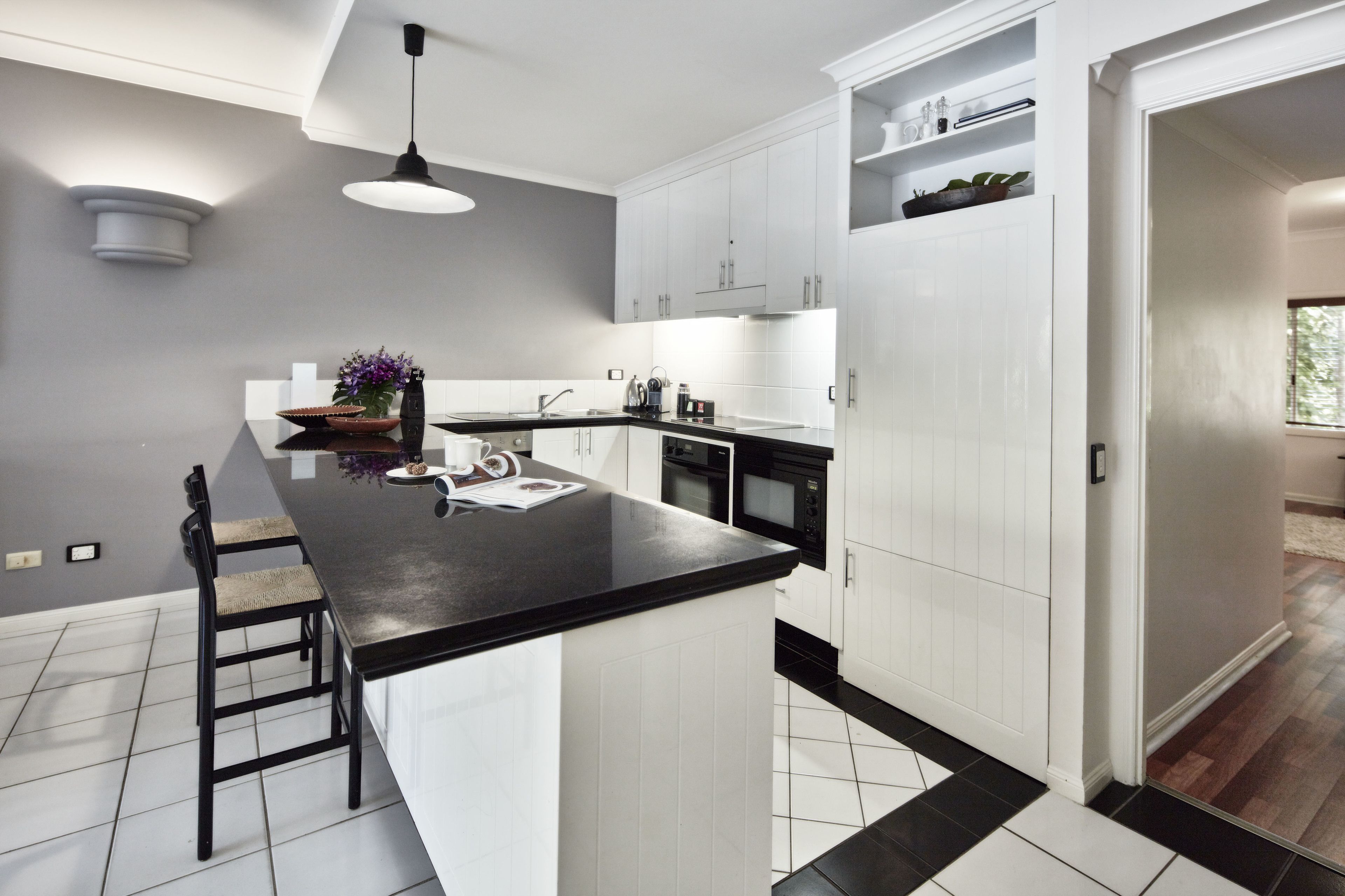 Une cuisine moderne avec des meubles blancs, un plan de travail noir et un îlot central.