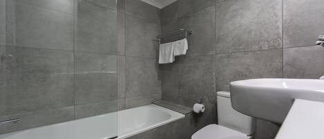 A modern bathroom with a bathtub, toilet, and sink.