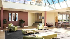 A spacious lobby with a high ceiling and skylight, featuring multiple seating areas and a staircase leading to upper floors. - ibis Styles Canberra Eaglehawk (Sutton)