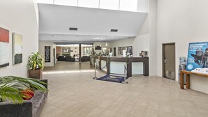A spacious lobby with a high ceiling, a reception desk, and a seating area. - ibis Styles Canberra Eaglehawk (Sutton)