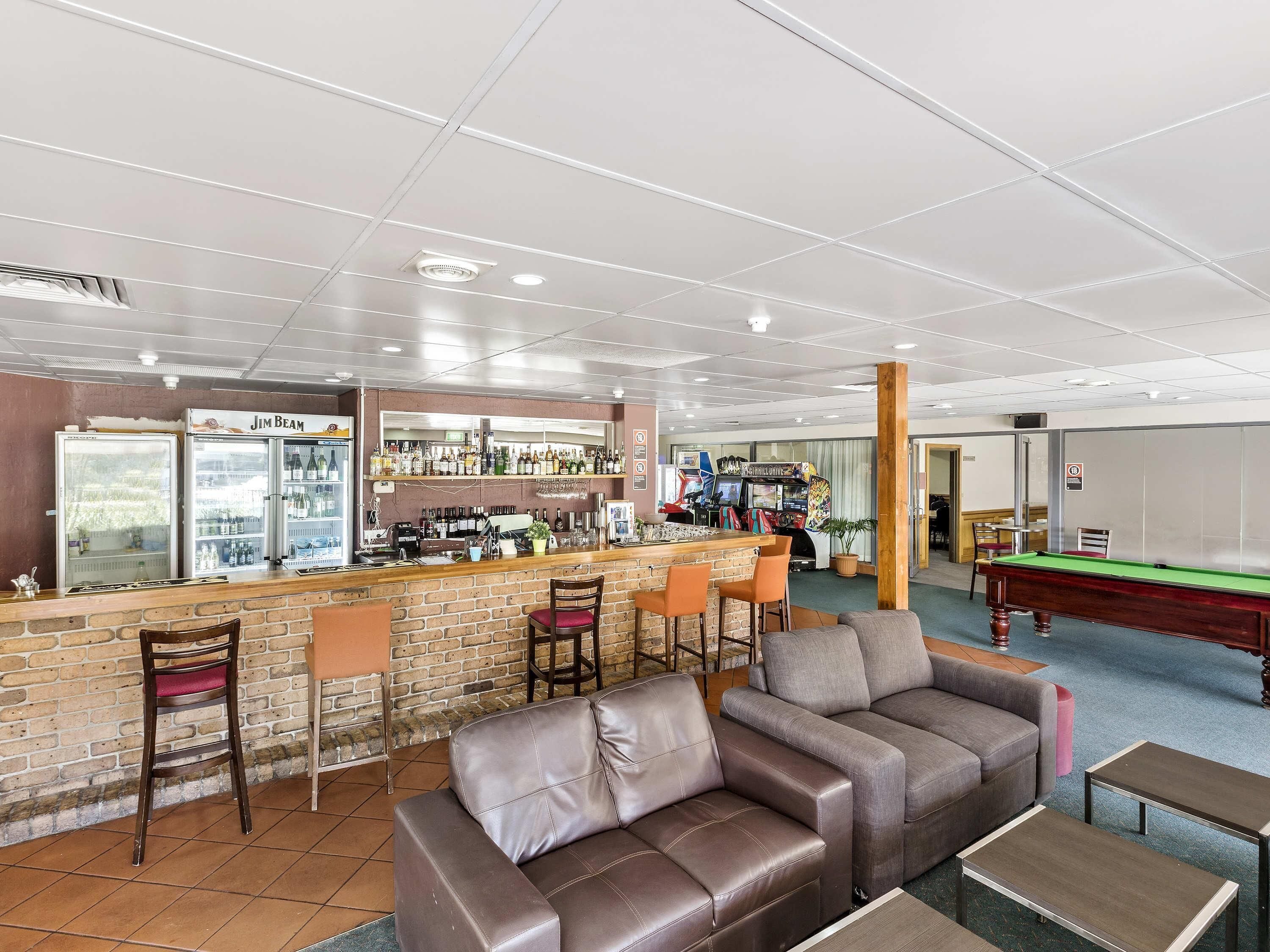 A bar area with a brick counter, seating, and a pool table.