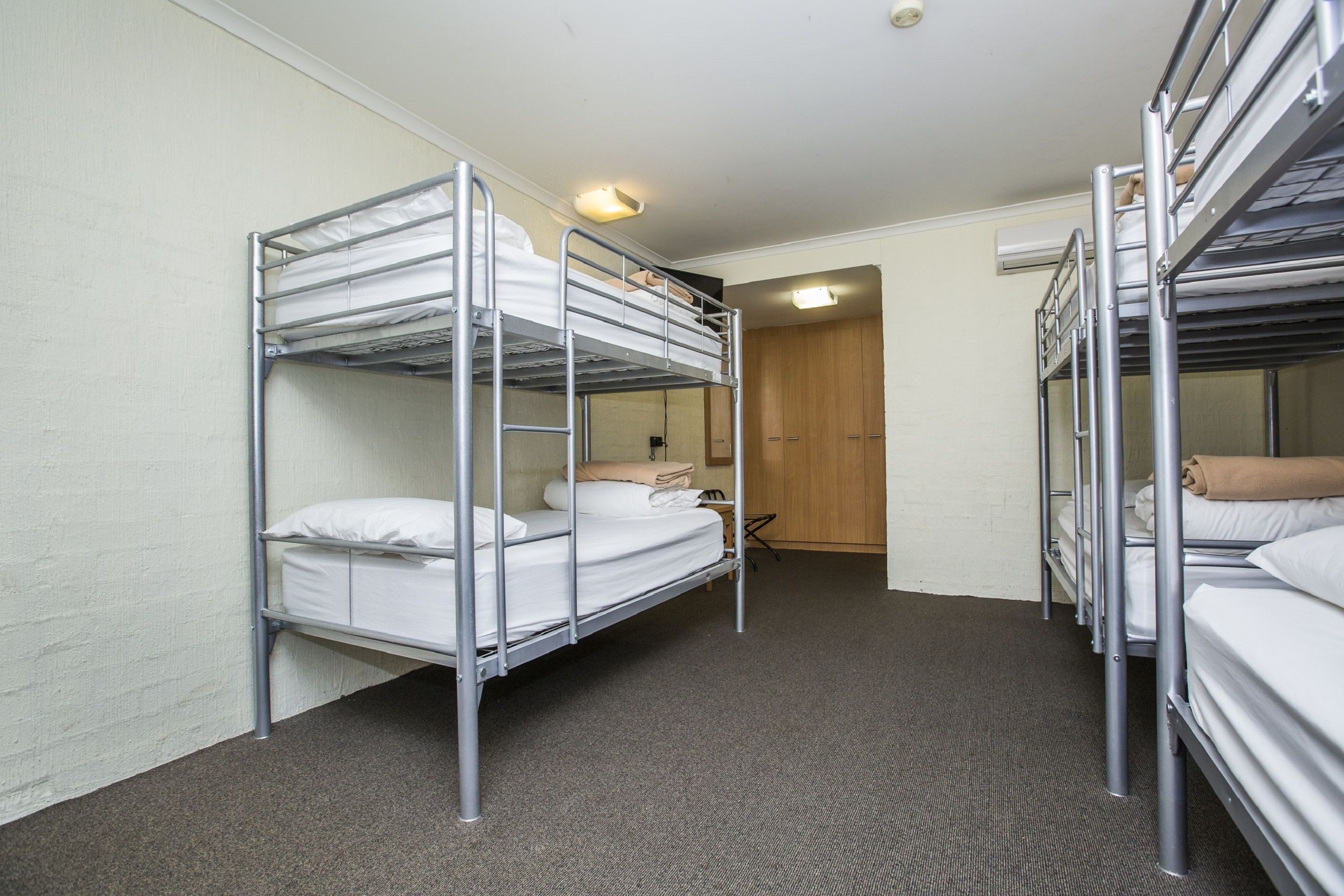 A room with bunk beds, a wooden door, and a carpeted floor.