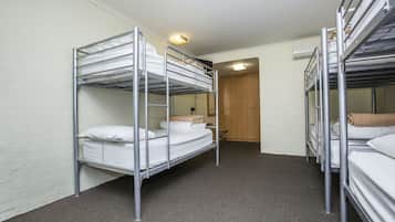 A room with bunk beds, a wooden door, and a carpeted floor.