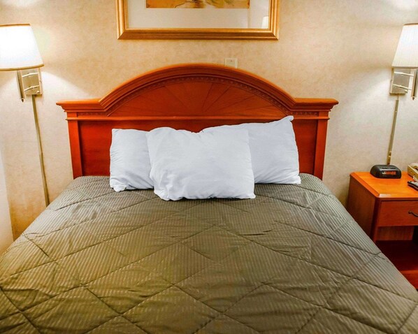 A neatly made bed with a quilted green bedspread and three white pillows. - Rodeway Inn Dillsburg (Dillsburg)