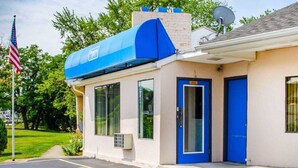 A building with a blue awning, a door labeled "Office," and a parking lot with marked spaces.