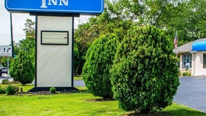 A sign for Rodeway Inn with a small building and well-maintained landscaping.