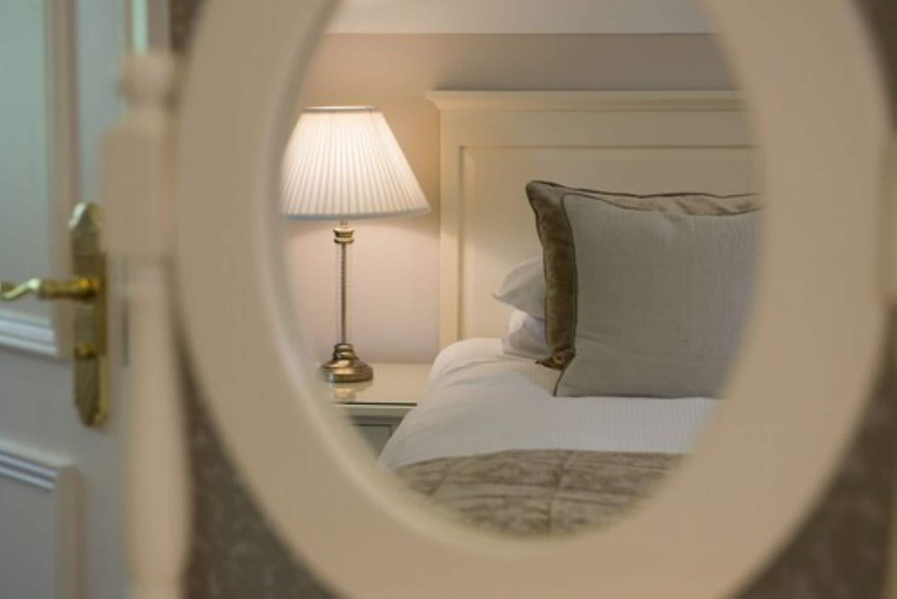 A hotel room with a bed, a nightstand, and a lamp.