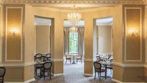 A grand hallway with ornate moldings, a chandelier, and a dining area with tables and chairs. - Bartley Lodge Hotel (Southampton)
