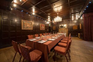 Un salón de conferencias con una larga mesa, sillas y un candelabro.