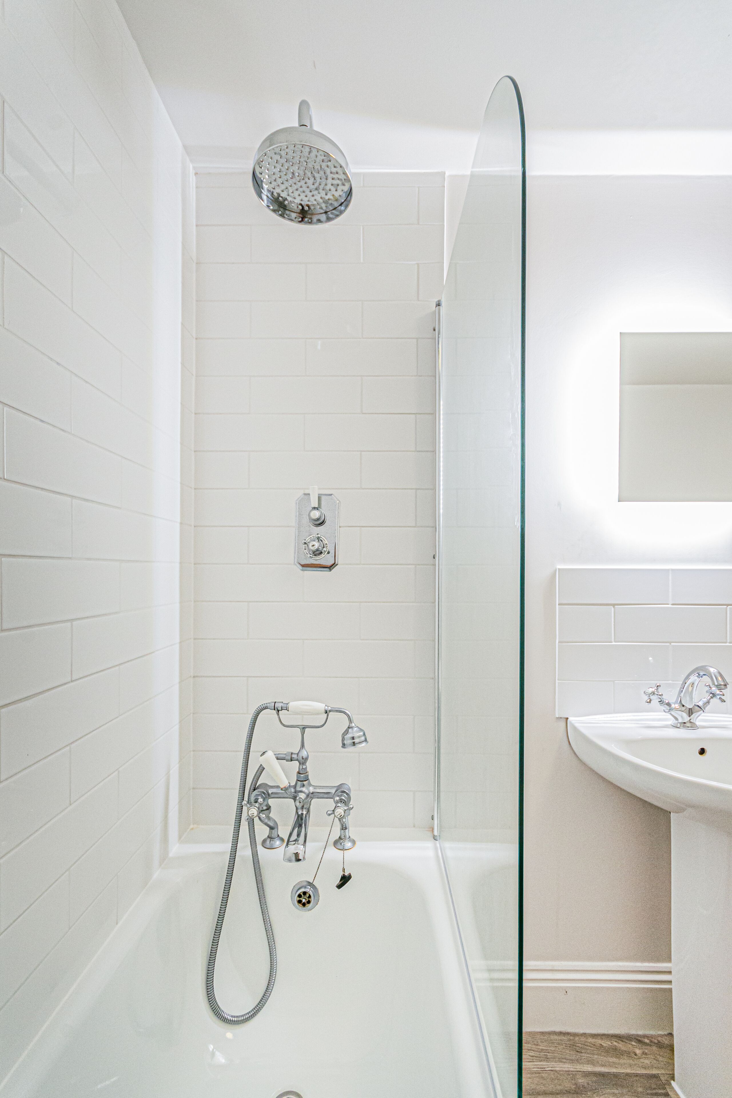 A modern bathroom with a glass shower enclosure, a separate sink, and a visible showerhead.