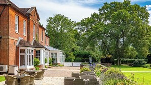 A brick building with a conservatory, outdoor seating, and a well-maintained garden. - Bartley Lodge Hotel (Southampton)