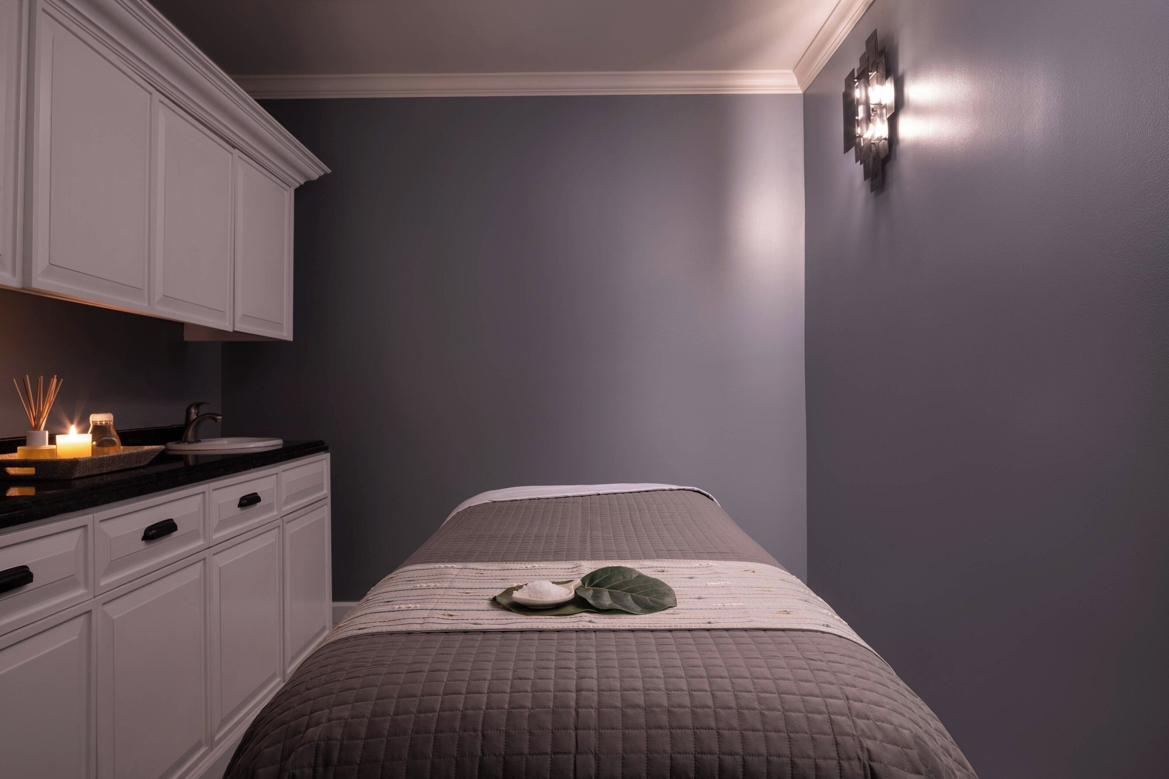 A bedroom with a bed, a nightstand, and a white dresser.